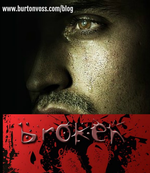 Dark view of man's face with tear track. Lower half of picture is in red with the word "broken" above a drawing of a heart.